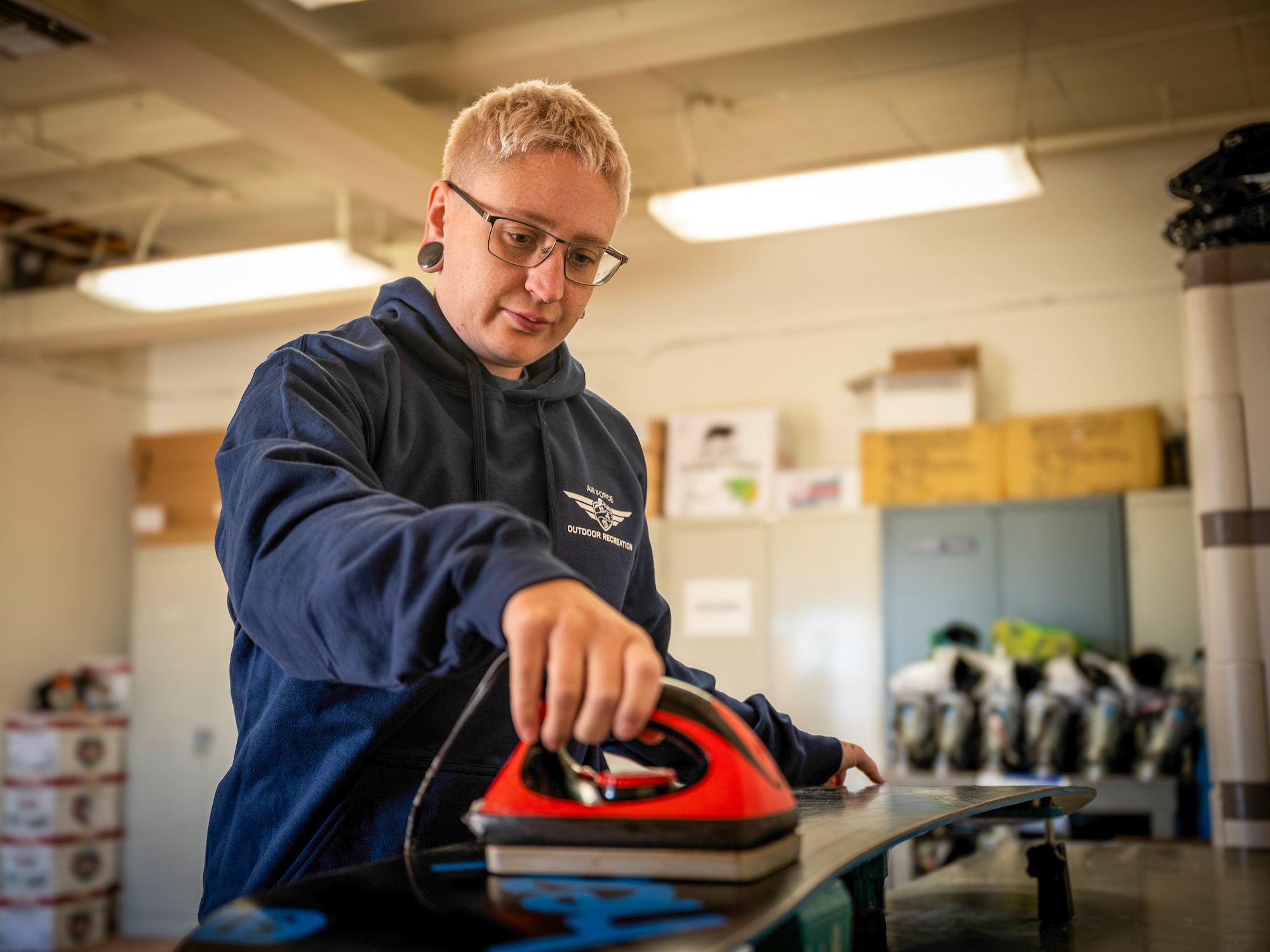 Tonie Sonderman, 412th Force Support Squadron customer service technician, smooths wax on a snowboard at the Outdoor Recreation facility on Edwards Air Force Base, California, March 10, 2026. The Edwards Outdoor Rec facility recently moved a new location to better facilitate base residents. (Air Force photo by Giancarlo Casem)