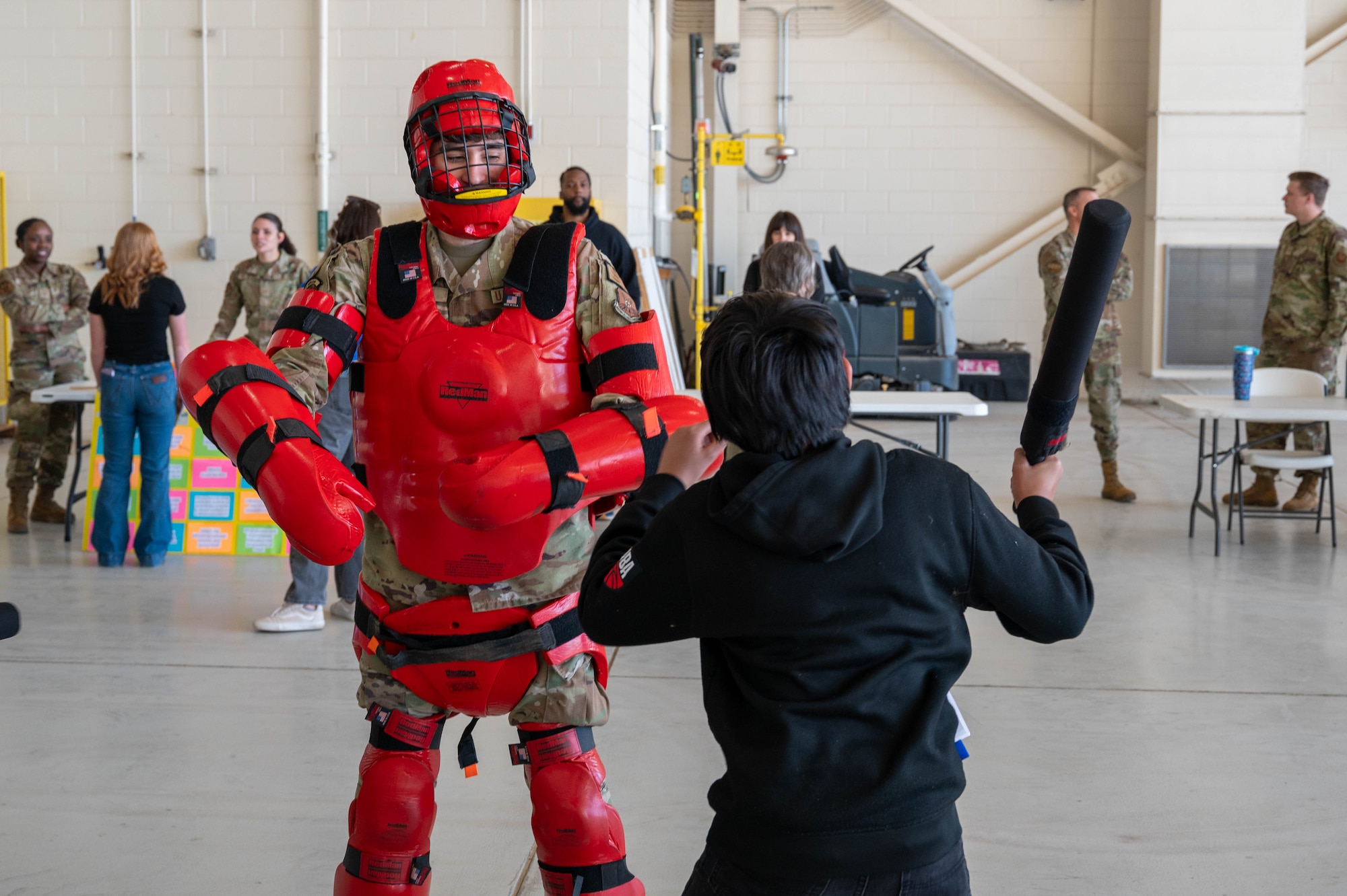 A U.S. Airman assigned to the 7th Security Forces Squadron demonstrates the red man full body protective suit to safely simulate realistic combat scenarios  with a student during a career fair at Dyess Air Force Base, Texas, Feb. 26, 2026. Students participated in demonstrations and viewed exhibits from 38 career fields during the event. (U.S. Air Force photo by Airman 1st Class William Neal)