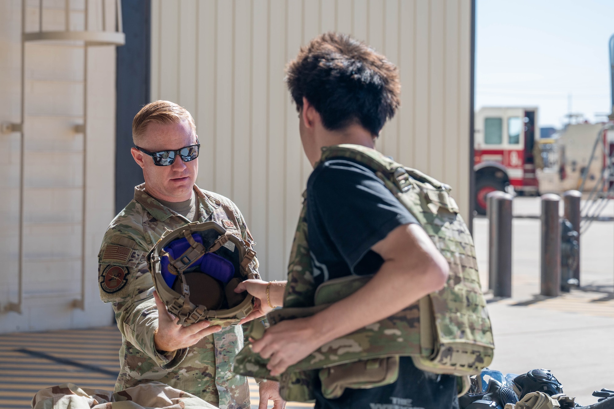 U.S. Air Force Senior Airman Channing Hoyt, 7th Logistics Readiness Squadron individual protective equipment journeyman, hands a helmet to a student during a career fair at Dyess Air Force Base, Texas, Feb. 26, 2026. The event invited students from the local area onto the installation to learn about career opportunities available in the Air Force. (U.S. Air Force photo by Airman 1st Class William Neal)