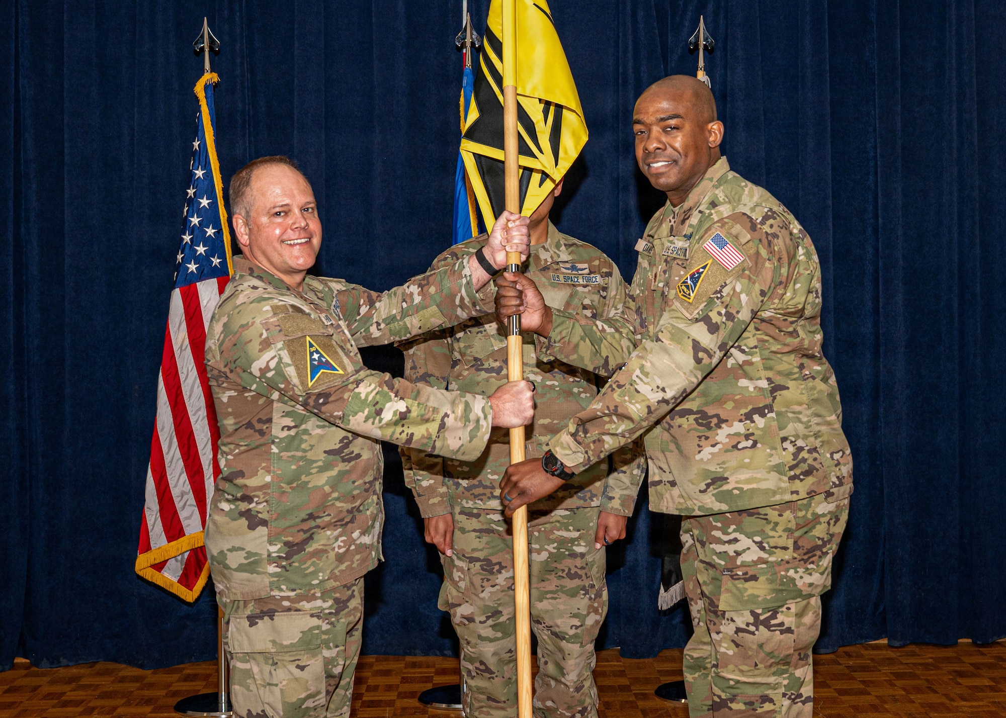 3 people stand on a stage and hold a flag