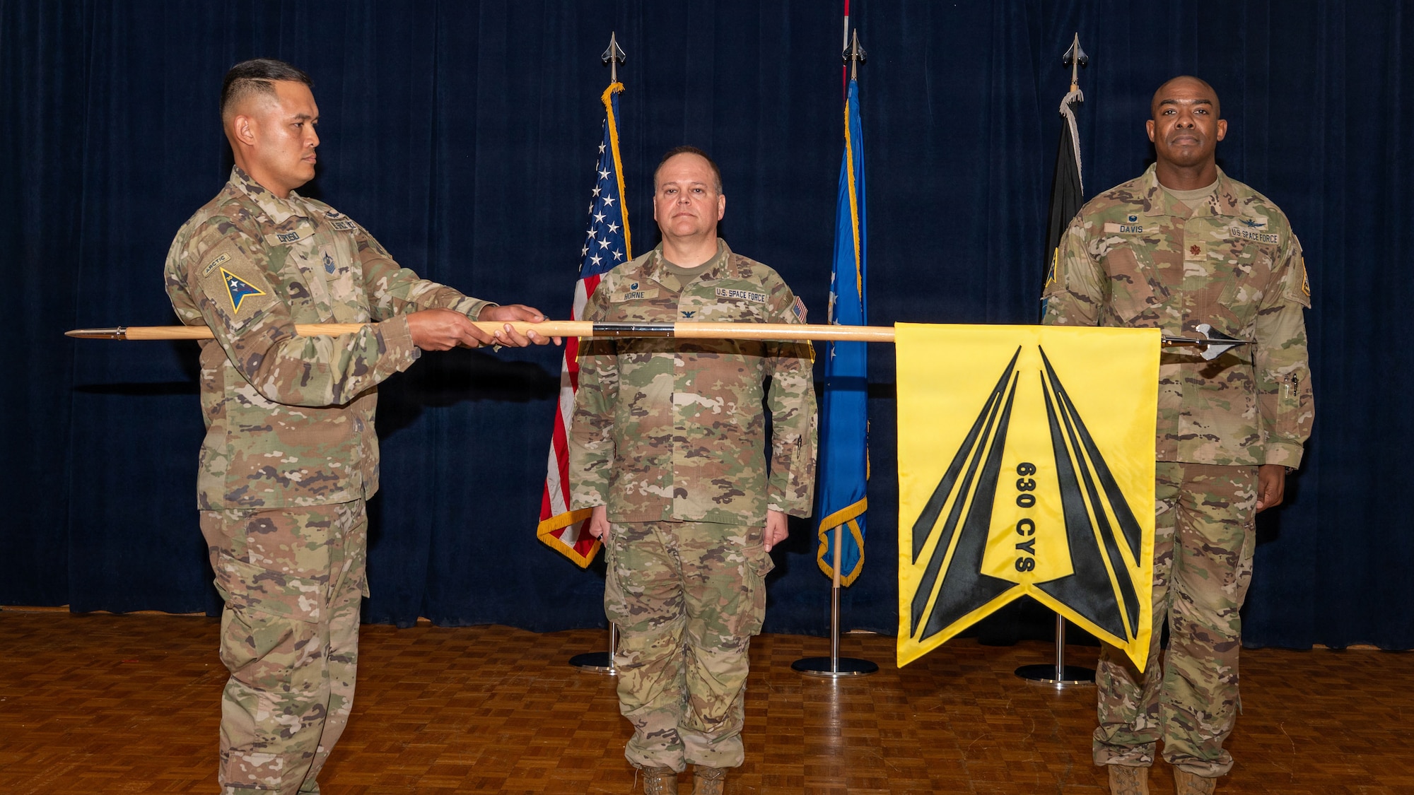 3 people stand on a stage and one extends out a flag