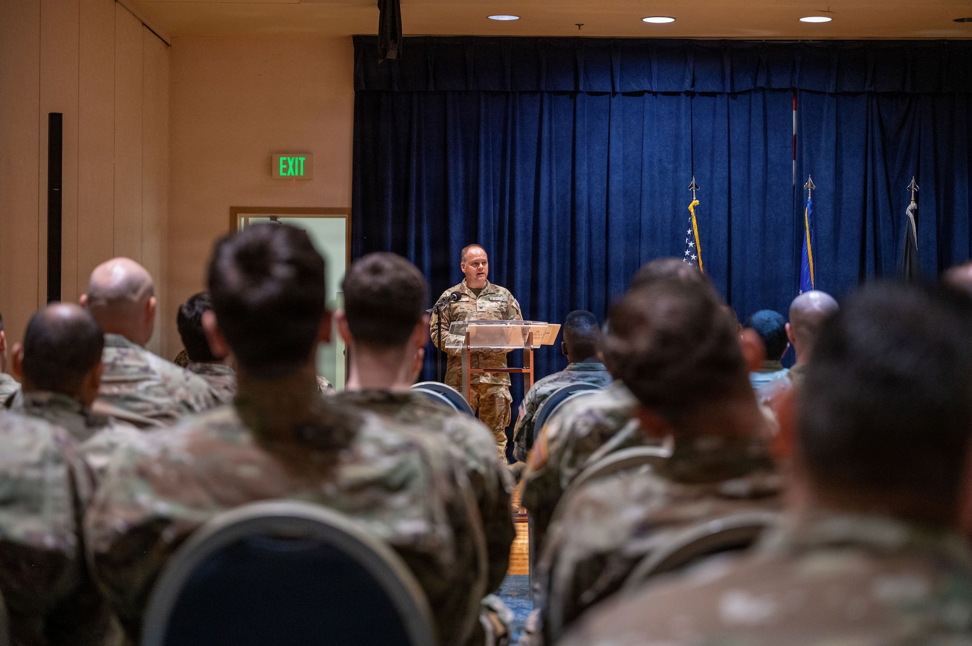 a person stands on a stage at a podium and speaks to a crowd