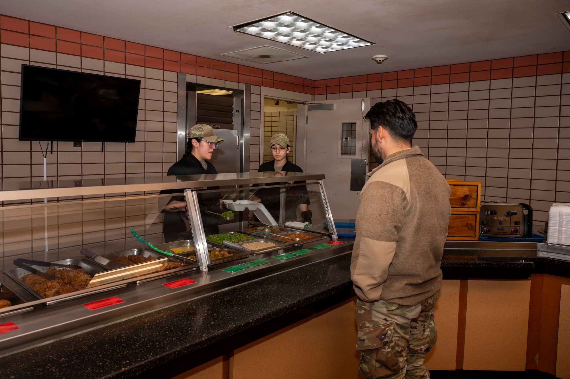 U.S. Air Force Senior Airmen Nya Mauvais (left) and Bailey Cuevas-Gluzman (middle), 354th Force Support Squadron food service journeymen, package a meal for an Airman at Eielson Air Force Base, Alaska, March 5, 2026.