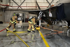 A photograph of firefighters training to extinguish battery fires on an F-35