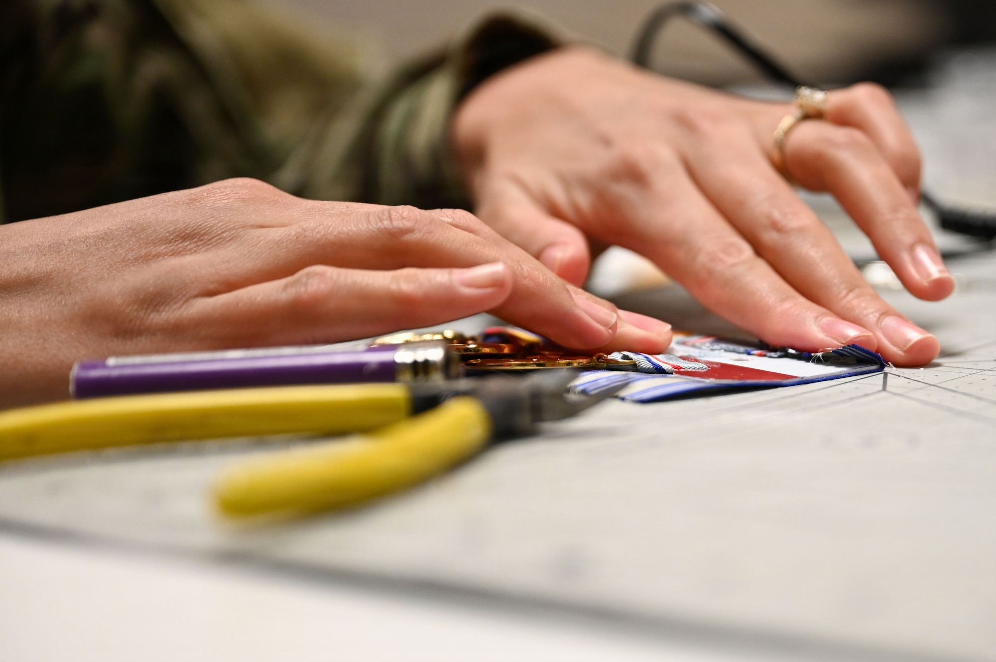 U.S. Air Force Airman 1st Class Kamya Dagami, a supply technician with the U.S. Air Force Honor Guard Supply, secures a medal to a ribbon rack at Joint Base Anacostia-Bolling, Washington, D.C., March 4, 2026. Since its inception, Honor Guard Supply has meticulously handcrafted custom medal sets in-house for each ceremonial guardsman to wear on their uniforms. (U.S. Air Force photo by Airman 1st Class Brandon Thomas)