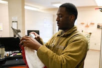 U.S. Air Force Senior Airman Darrell Knight Jr., a supply technician with the U.S. Air Force Honor Guard Supply, secures a flag to a flagpole at Joint Base Anacostia-Bolling, Washington, D.C., March 4, 2026. Created in 1948 to support the newly-formed Air Force Honor Guard, Honor Guard Supply prepares flags for upcoming missions, issues uniform items and inspects vehicles, among many other responsibilities. (U.S. Air Force photo by Airman 1st Class Brandon Thomas)