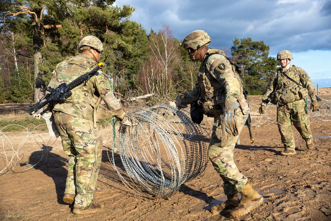 Soldiers assigned to 15th Engineer Battalion, 7th Engineer Brigade, participate in building the triple standard concertina wire at the Grafenwoehr Training Area.