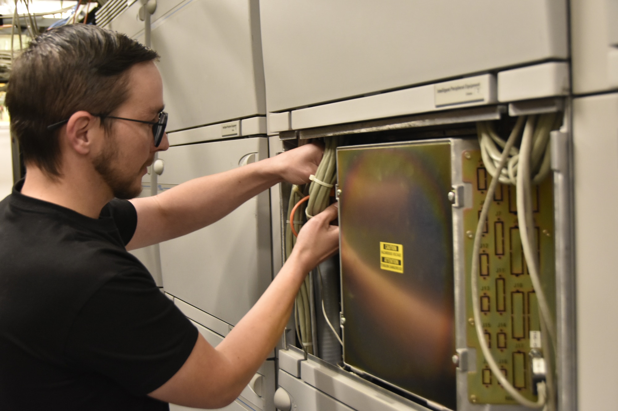 Drew Savelle, telecommunications technician for the Base Communications and Information Technology contractor at Arnold Air Force Base, Tenn., works Sept. 19, 2025, on the digital phone switch network installed as part of a telecommunications upgrade. Along with the new network, new Voice over Internet Protocol phones were deployed to users across Arnold.  (U.S. Air Force photo by Brad Hicks)