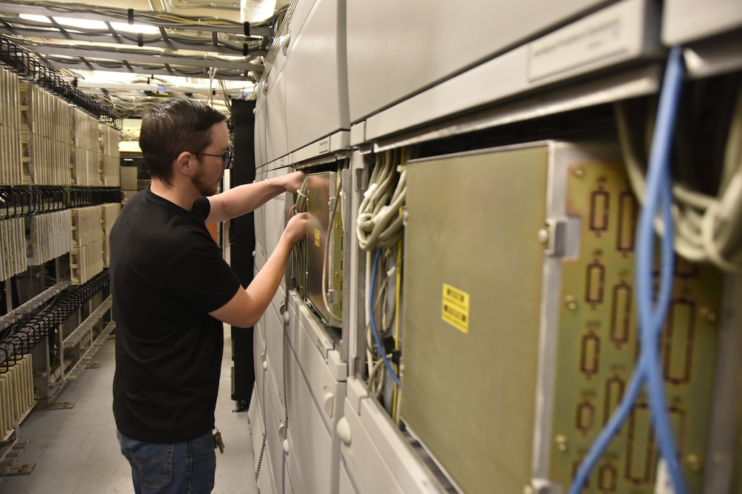 Drew Savelle, telecommunications technician for the Base Communications and Information Technology contractor at Arnold Air Force Base, Tenn., works Sept. 19, 2025, on the digital phone switch network installed as part of a telecommunications upgrade. Along with the new network, new Voice over Internet Protocol phones were deployed to users across Arnold.  (U.S. Air Force photo by Brad Hicks)