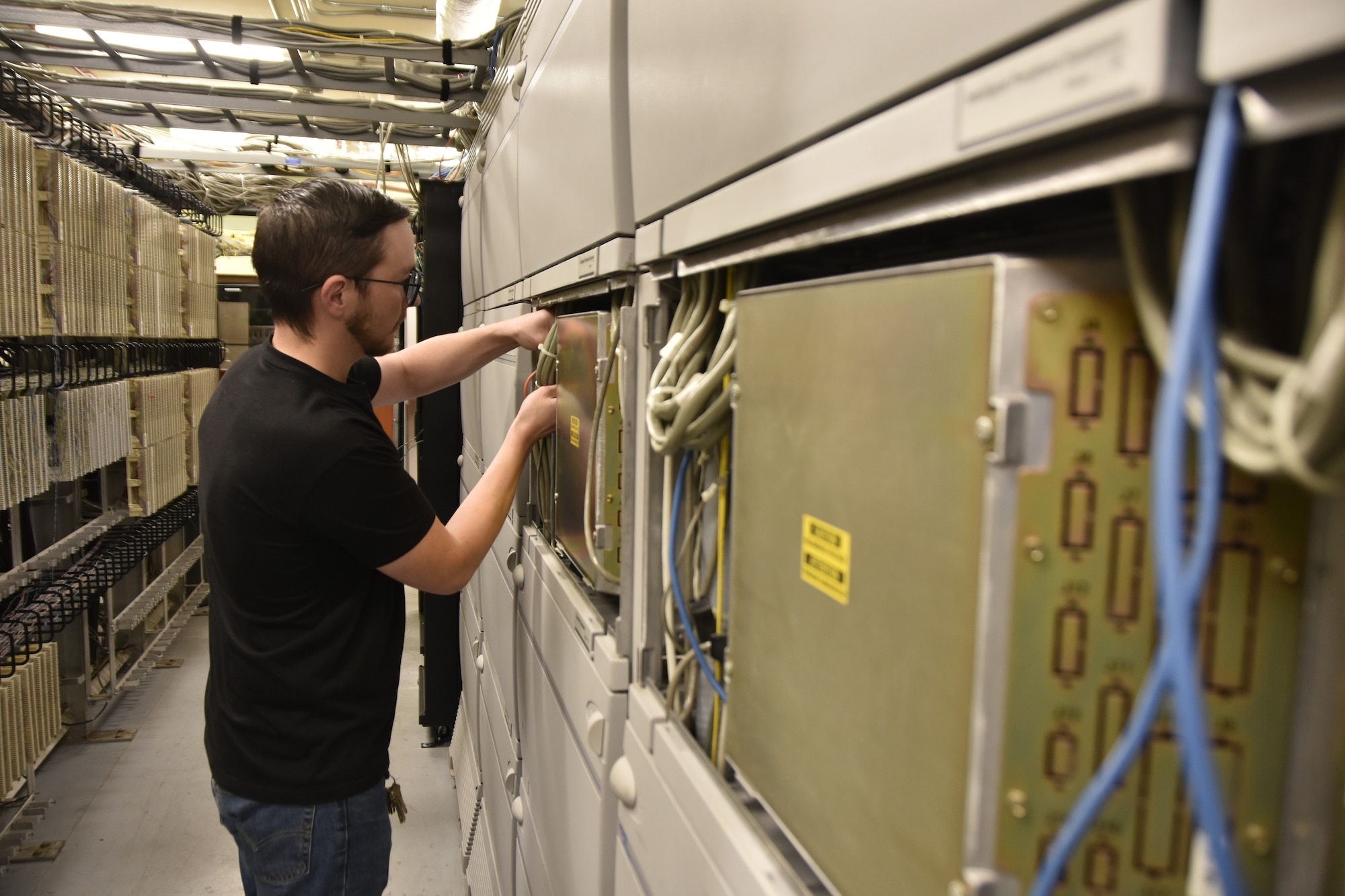 Drew Savelle, telecommunications technician for the Base Communications and Information Technology contractor at Arnold Air Force Base, Tenn., works Sept. 19, 2025, on the digital phone switch network installed as part of a telecommunications upgrade. Along with the new network, new Voice over Internet Protocol phones were deployed to users across Arnold.  (U.S. Air Force photo by Brad Hicks)