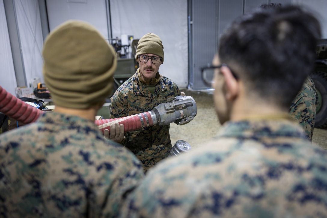 U.S. Marine Corps Chief Warrant Officer 4 Carl Snyder, a bulk fuels officer with 6th Engineer Support Battalion, 4th Marine Logistics Group, Marine Forces Reserve, explains the function of a four-foot dry-break suction hose to Marines in Elvegårdsmoen, Norway, Feb. 26, 2026. The instruction was part of the unit's preparation for exercise Cold Response 26. A key component of NATO's enhanced vigilance activity Arctic Sentry, exercise Cold Response 26 is a Norwegian-led winter military exercise designed to enhance collective defense capabilities and ensure U.S. readiness to rapidly deploy and seamlessly operate alongside NATO Allies in challenging arctic conditions. (U.S. Marine Corps photo by Staff Sgt. Scott Jenkins)