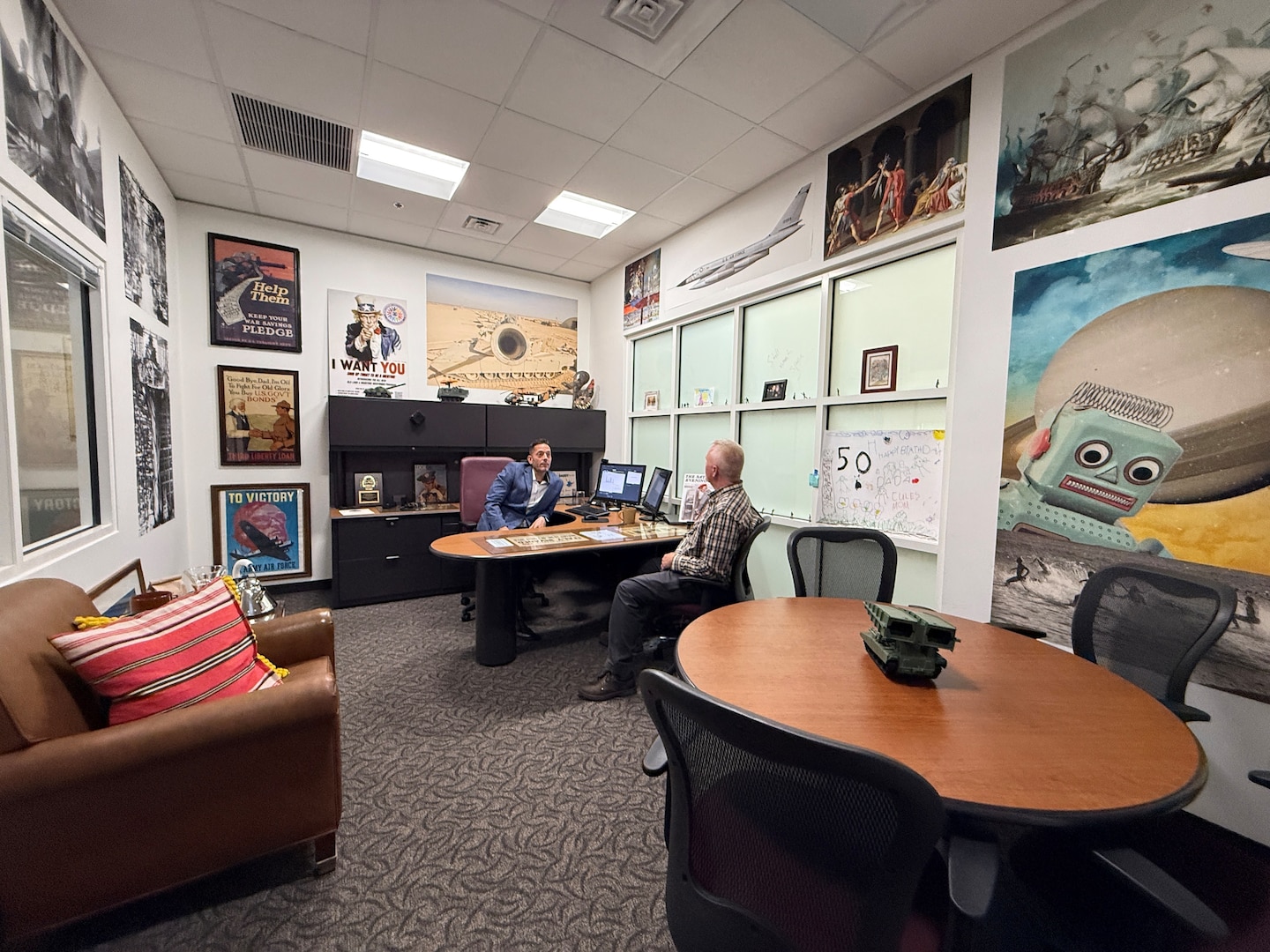 Two men sit at a desk in an office