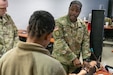 U.S. Army Reserve Sgt. 1st Class Jerry Flanders, right, a combat medic assigned to the Pinellas Park, Fla., based Army Reserve Medical Command, demonstrates to other combat medics how to set up and perform a blood extraction on a manikin arm during the Military Occupational Specialty, or MOS, 68W Sustainment Course held at Fort McCoy, Wis., Feb. 24, 2026. AR-MEDCOM Soldiers — in coordination with the Fort McCoy, Wis., based Medical Simulation and Training Course — developed and executed an ad hoc solution to ensure timely recertification and revalidation of combat medic skills to all MOS 68W Army Reserve and Army National Guard Soldiers. (U.S. Army Reserve photo by Sgt. 1st Class Christopher A. Hernandez)