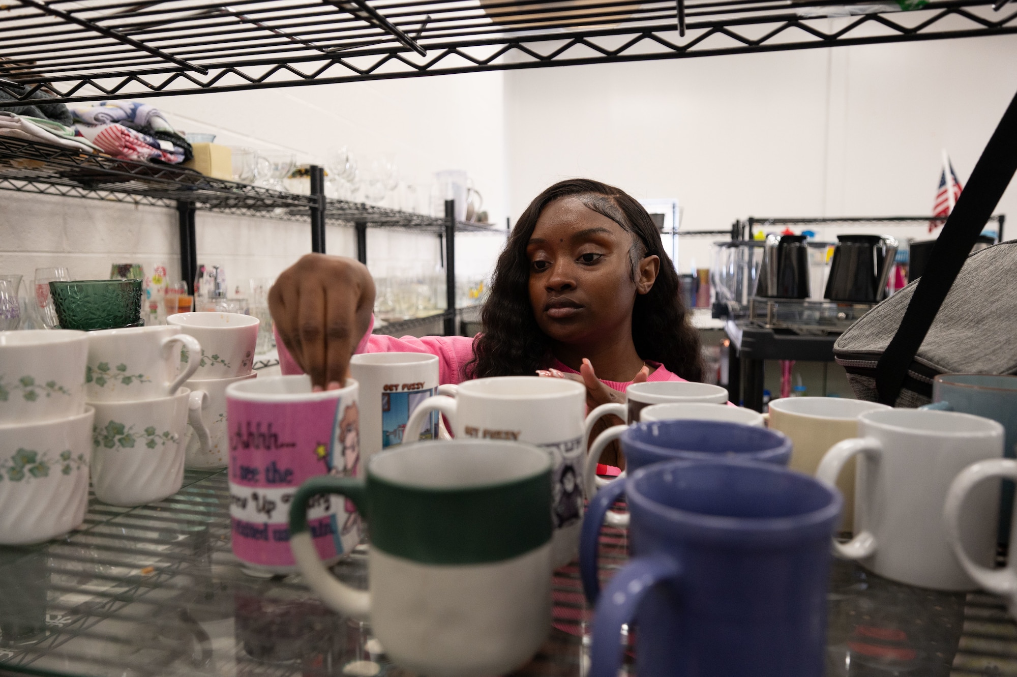 U.S. Air Force Senior Airman Tori McLeary, 436th Comptroller Squadron financial analyst, organizes mugs at the Airmen’s Attic at Dover Air Force Base, Delaware, Feb. 21, 2026. Mcleary volunteers many hours towards the Airmen’s Attic, putting that time to good use by organizing donations, checking people in at the front desk and cleaning different spaces. (U.S. Air Force photo by Airman 1st Class Liberty Kuhn)