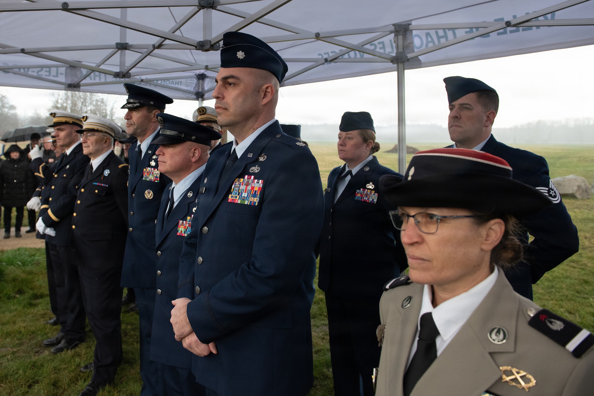 Photo shows several French residents and U.S. Airmen gathered outdoors for a memorial ceremony.