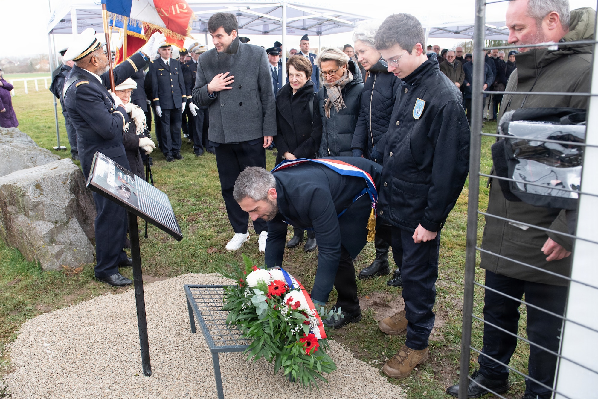 Photo shows several French residents and U.S. Airmen gathered outdoors for a memorial ceremony.