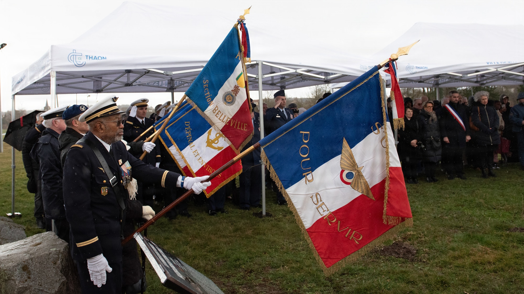 Photo shows several French residents and U.S. Airmen gathered outdoors for a memorial ceremony.