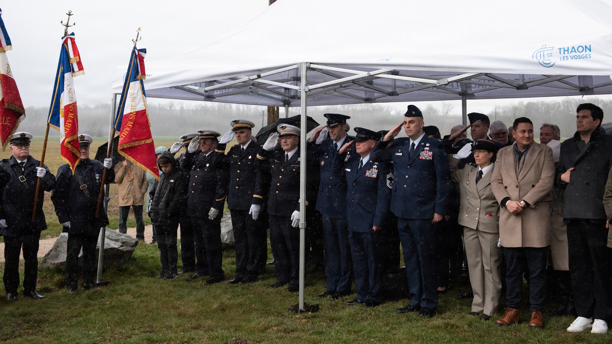 Photo shows several French residents and U.S. Airmen gathered outdoors for a memorial ceremony.