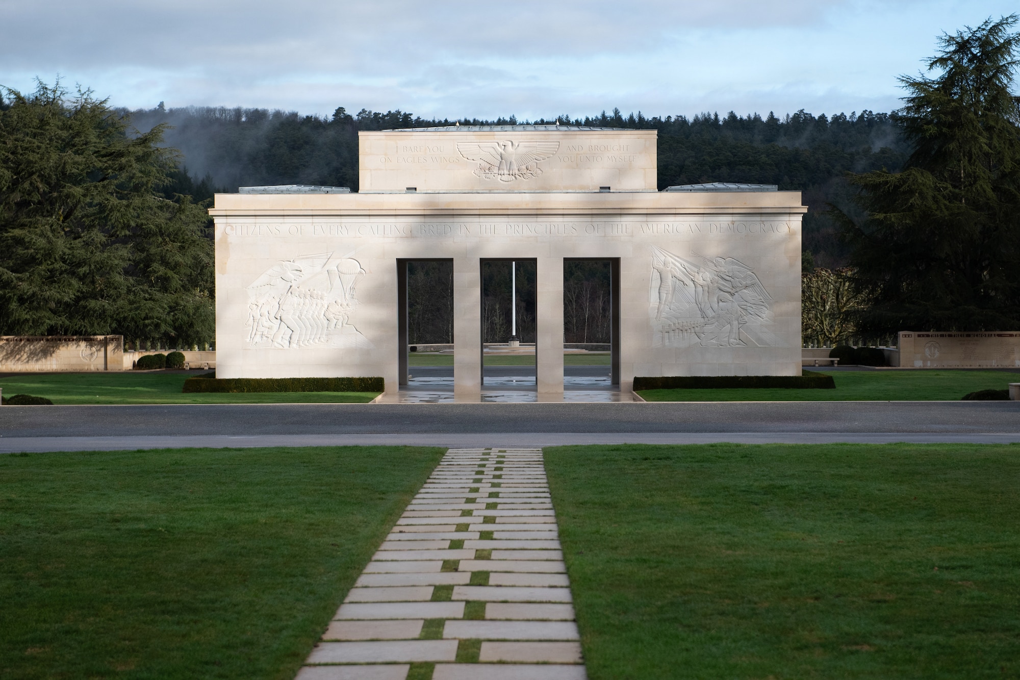 Photo shows a stone structure that serves as a memorial building at the entrance of a cemetery created to inter American servicemembers lost during World War II.