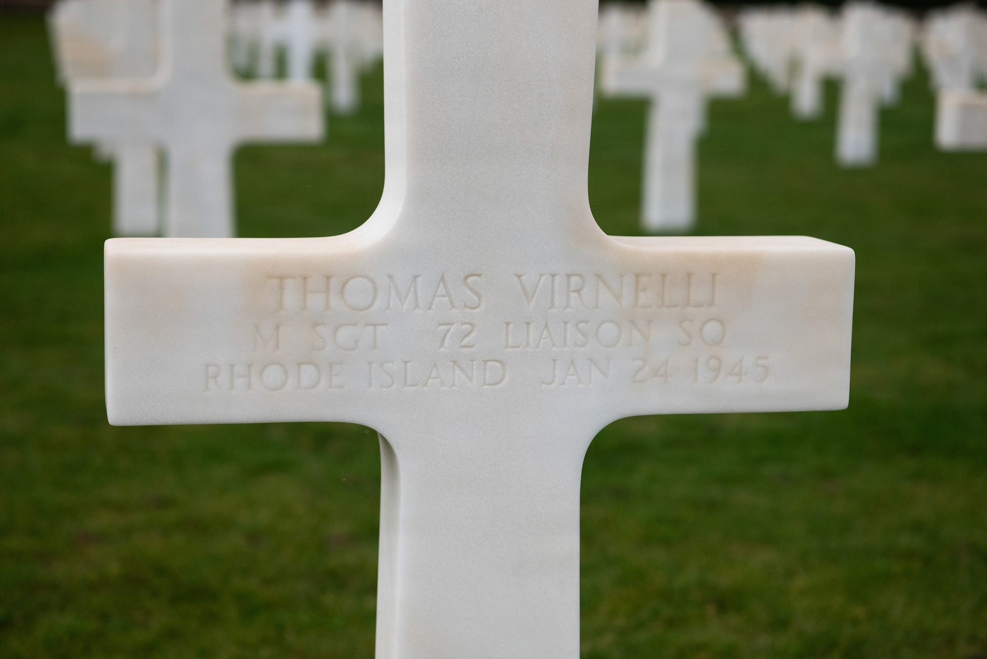 Photo shows an etching of information on a white marble cross marking the grave of an American Airman lost during World War II.
