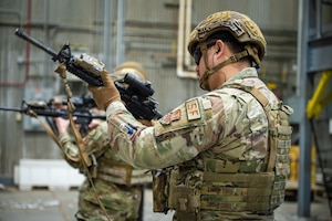 A uniformed man holds an M4 rifle.