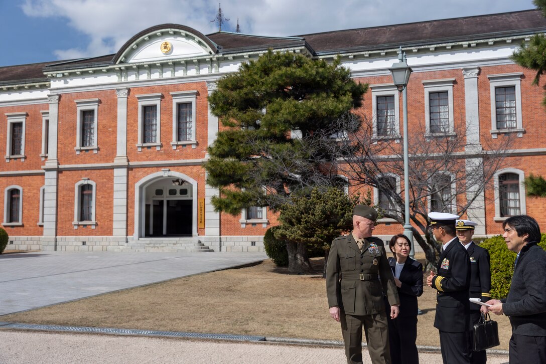 U.S. Marine Corps Col. Kenneth Rossman, center, the commanding officer of Marine Corps Air Station Iwakuni and a native of Pittsburgh, Pennsylvania, speaks with Japan Maritime Self-Defense Force leadership in front of Red Brick Students Hall, the Museum of Naval History, at Etajima, Hiroshima Prefecture, Japan, March 4, 2026. The visit provided U.S. military leadership the opportunity to observe how Japan Maritime Self-Defense Force cadets are trained and developed, gaining perspective on Japanese naval education and leadership while strengthening command relationships and reinforcing the U.S. Japan alliance. (U.S. Marine Corps photo by Lance Cpl. Isaac De Leon)