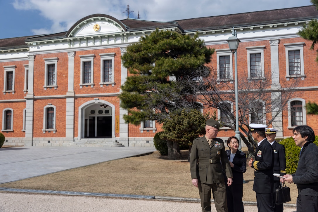 U.S. Marine Corps Col. Kenneth Rossman, center, the commanding officer of Marine Corps Air Station Iwakuni and a native of Pittsburgh, Pennsylvania, speaks with Japan Maritime Self-Defense Force leadership in front of Red Brick Students Hall, the Museum of Naval History, at Etajima, Hiroshima Prefecture, Japan, March 4, 2026. The visit provided U.S. military leadership the opportunity to observe how Japan Maritime Self-Defense Force cadets are trained and developed, gaining perspective on Japanese naval education and leadership while strengthening command relationships and reinforcing the U.S. Japan alliance. (U.S. Marine Corps photo by Lance Cpl. Isaac De Leon)