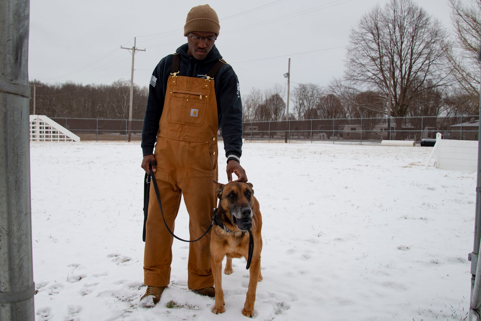Senior Airman Johnson and MWD Bulit stand side by side in the snow.