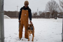 Senior Airman Johnson and MWD Bulit stand side by side in the snow.