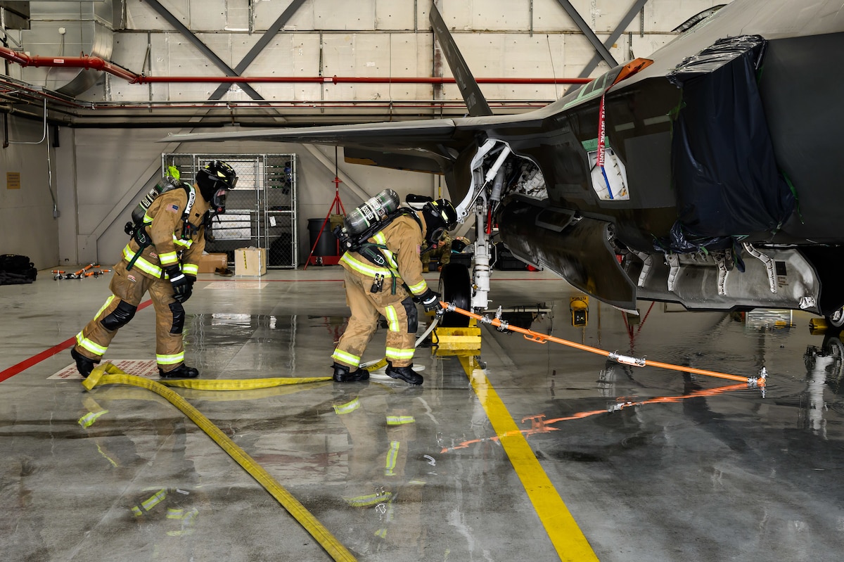 A photograph of firefighters training to extinguish battery fires on an F-35