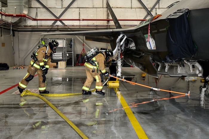 A photograph of firefighters training to extinguish battery fires on an F-35