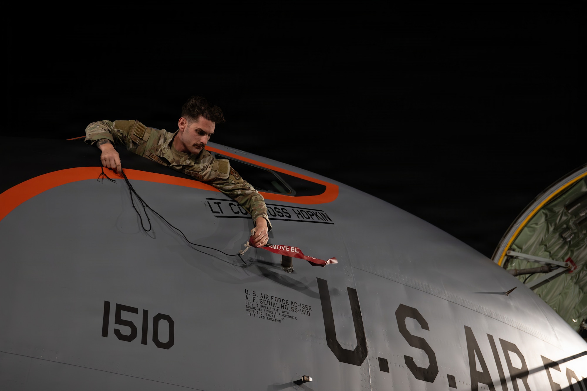 An Airman attaches equipment to an aircraft.