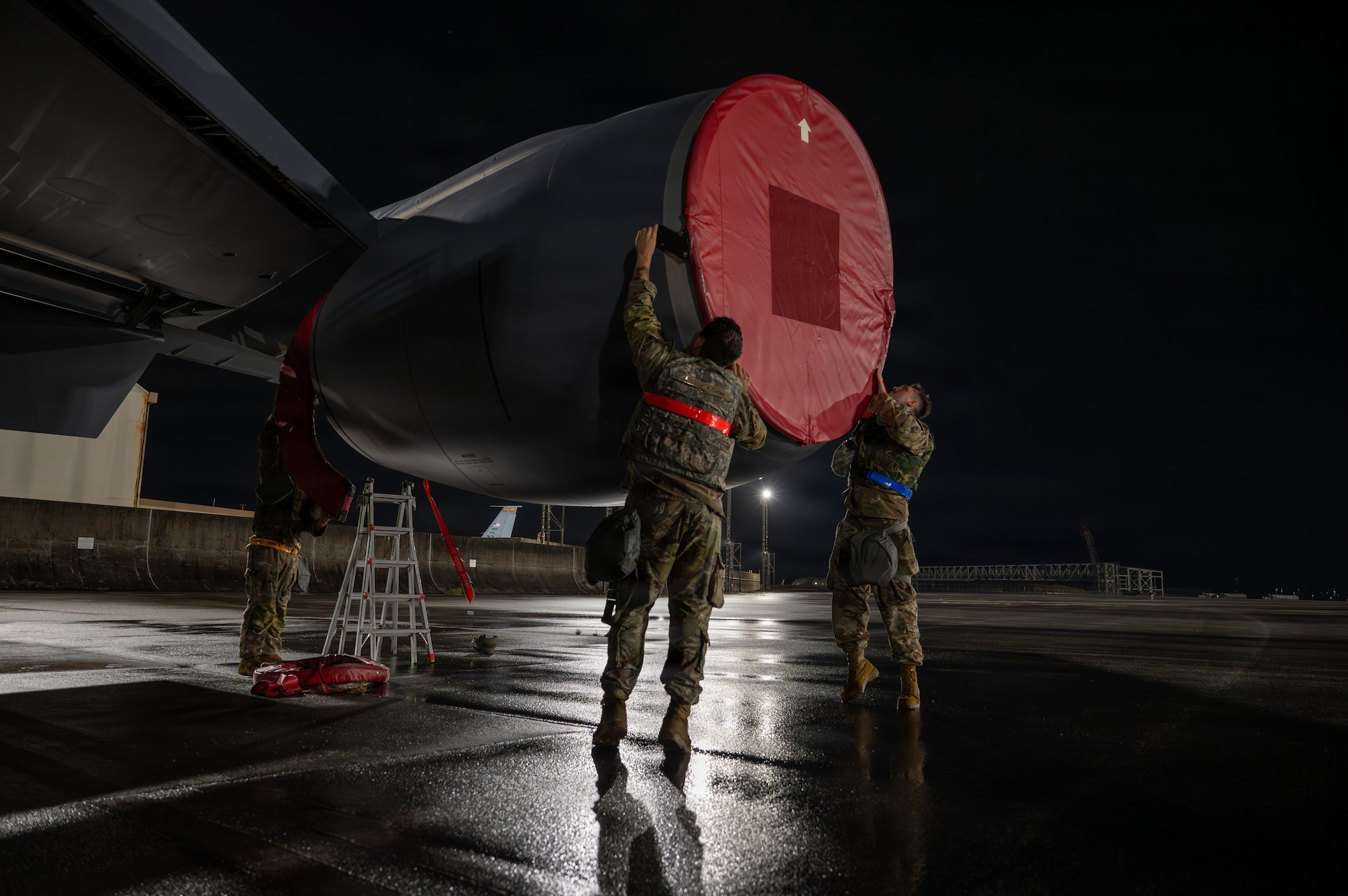 Airmen place engine covers on an aircraft.