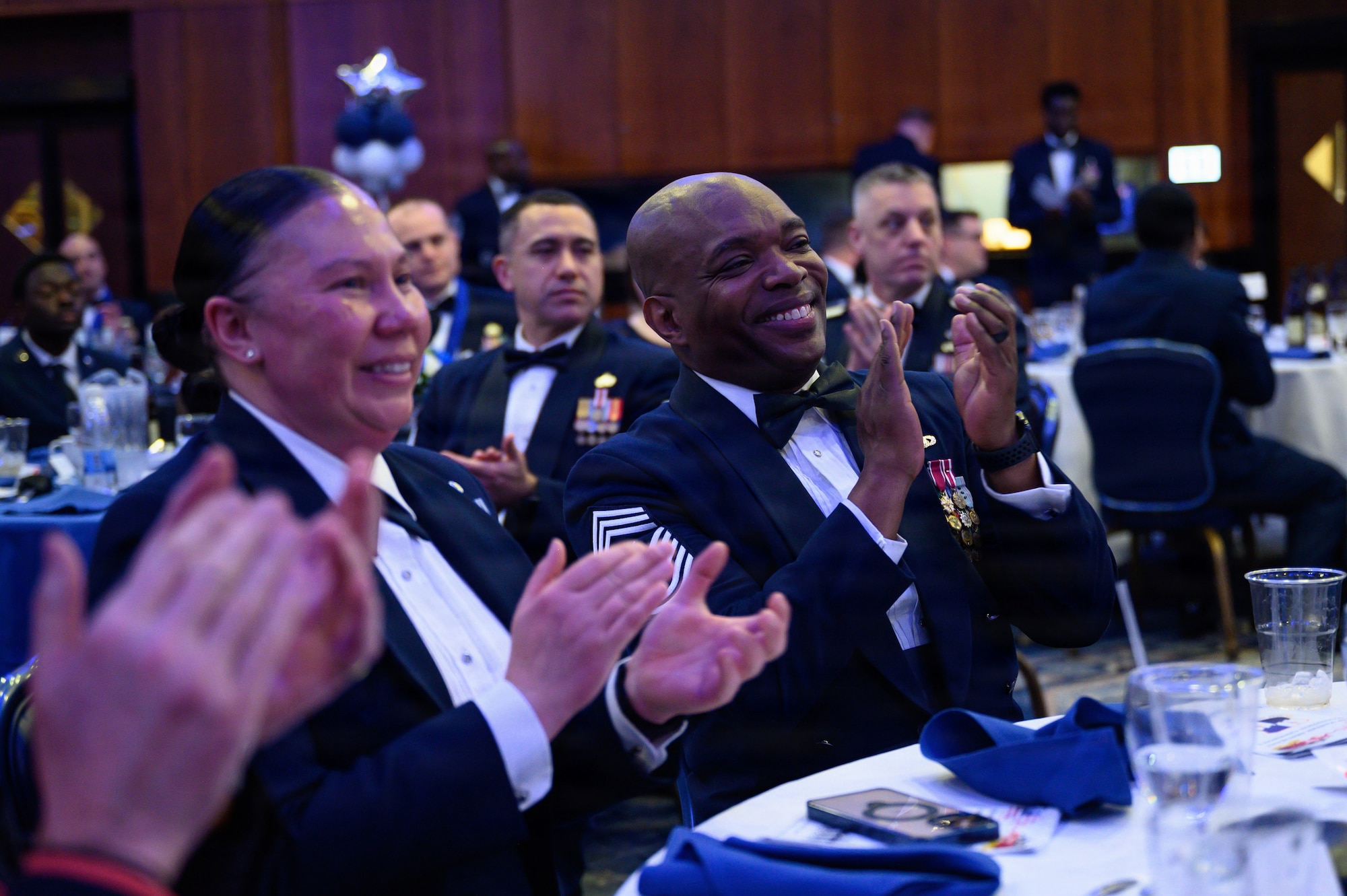 Two Command Chief Master Sergeants give applause during a formal ceremony.