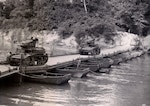 Tanks cross a bridge over a river