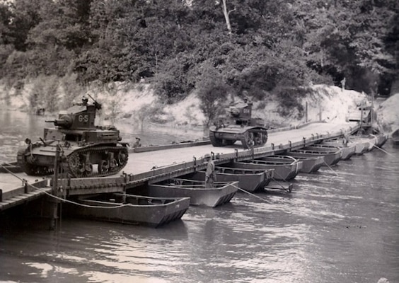 Tanks cross a bridge over a river