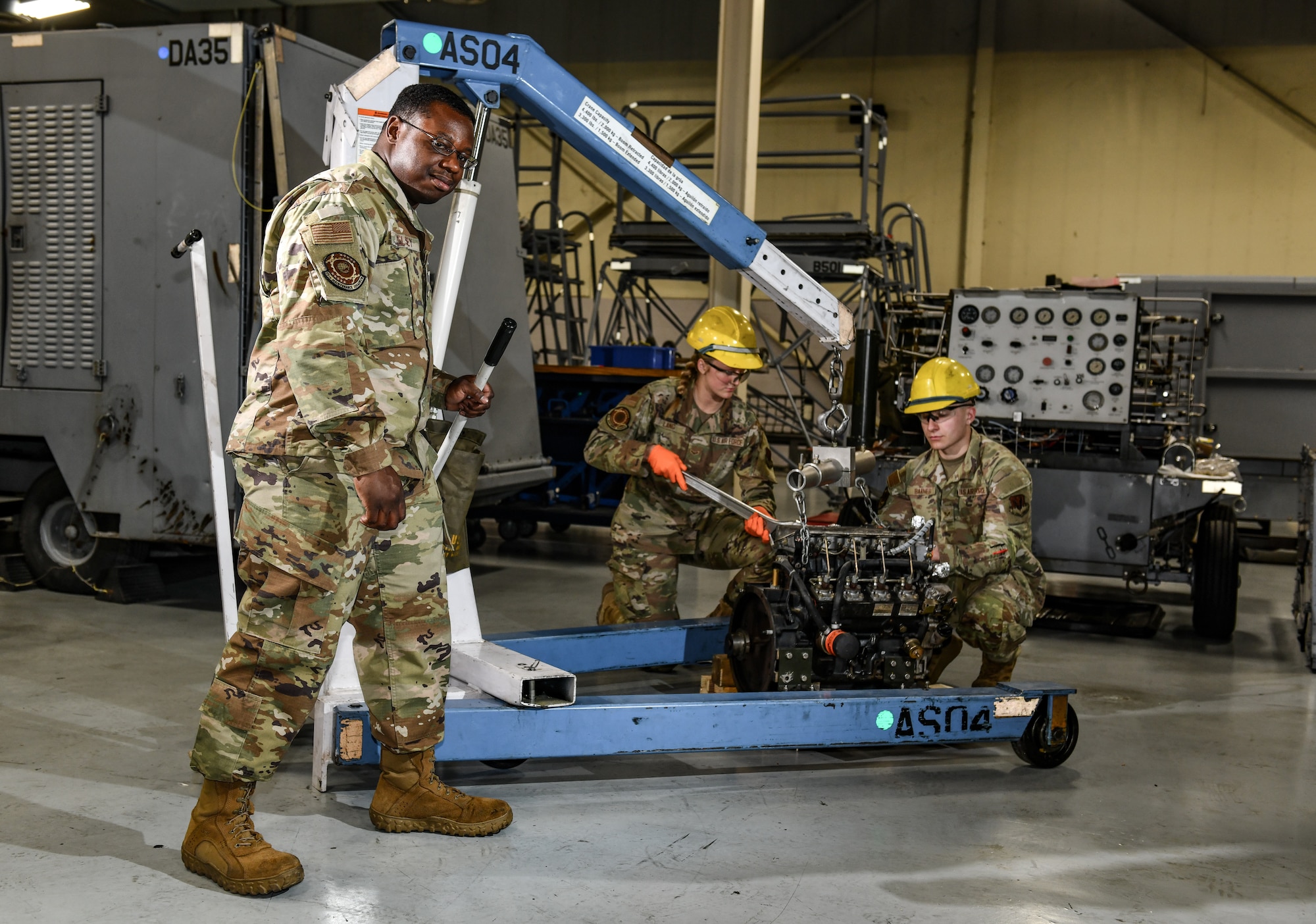 Technical Sgt. Deshaun Pelsey helps hoist an engine as Airman 1st Class Hanah Lang and Senior Airman Johnathan Barnes  prepare it to be installed on a nitrogen servicing cart at the Bennie L. Davis Maintenance facility on Offutt Air Force Base, March 5, 2026. Aerospace Ground Equipment technicians in the 55th Maintenance Squadron inspect, repair, and maintain the essential non-aircraft equipment used to power, support, and service aircraft while on the ground. AGE specialists are often considered jacks of all trades due to their diverse array or systems that the work with. (U.S. Air Force photo by Chad Watkins)