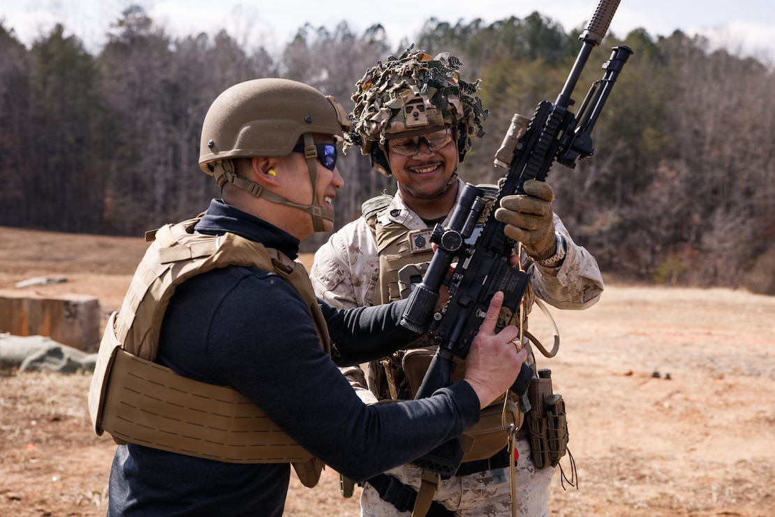 The Honorable Hung Cao, Under Secretary of the Navy, left, is handed an M27 Infantry Automatic Rifle from U.S. Marine Corps Staff Sgt. Basiru Garner, assault amphibious vehicle crewmember with The Basic School, Training Command, at Marine Corps Base Quantico, Virginia, Feb. 27, 2026. During a visit to TBS and Officer Candidates School, Cao met with senior leaders and Marines to observe training and gain a deeper understanding of the methods the Marine Corps uses to train, screen, and evaluate its candidates and newly commissioned officers. (U.S. Marine Corps photo by Cpl. Joshua Barker)