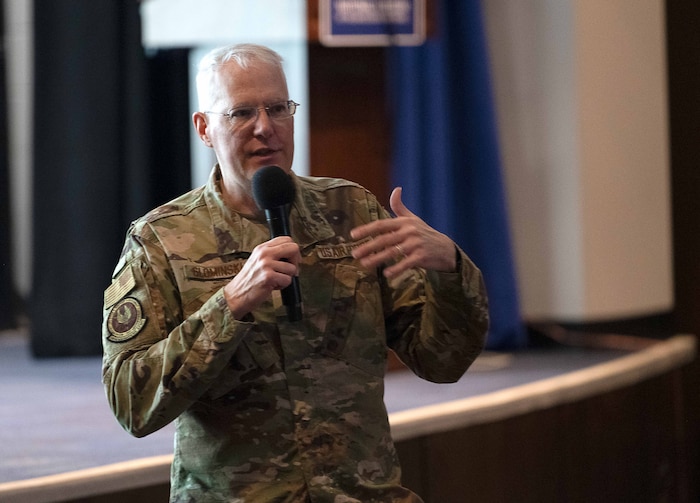 A uniformed Airman speaks into a microphone.