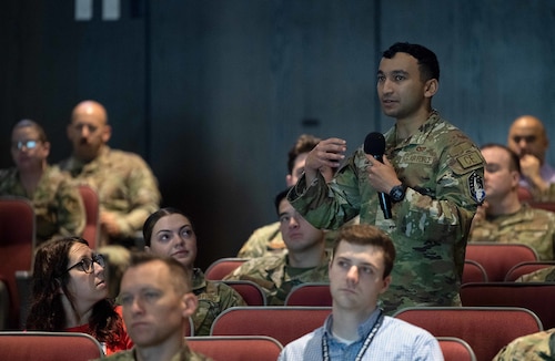 A uniformed Airman speaks into a microphone.