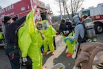 Clackamas and Gresham firefighters prepare to work in a contaminated zone by donning protective chemical suits during response procedures in an Air Monitoring Exercise on Feb. 26, 2026, in Clackamas, Oregon.
