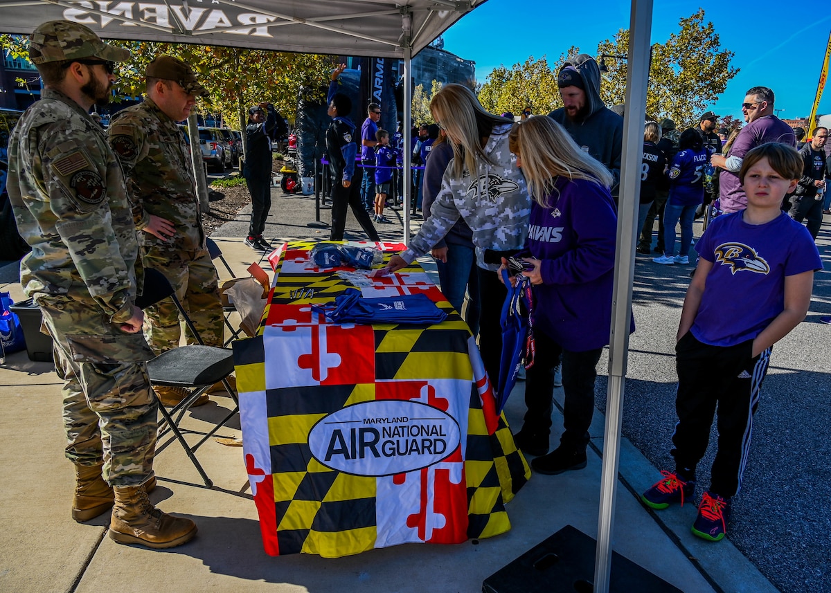 Two Maryland Air National Guard recruiters from the 175th Wing speak at a booth outside the M&T Bank Stadium before a Baltimore Ravens NFL game in Baltimore, Maryland, November 3, 2024. These recruiters have attended many local football and baseball games with their team in an effort to reach out to the community and inform the public of opportunities in the Air National Guard. (U.S. Air National Guard Photo by Airman 1st Class Sarah Hoover)