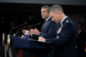 Secretary of War Pete Hegseth speaks at a lectern beside Air Force Gen. Dan Caine at another one.