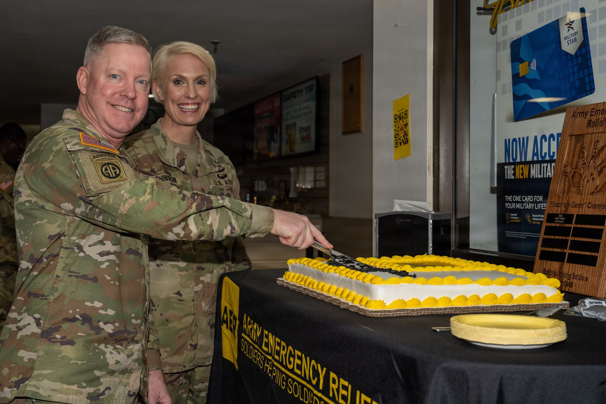 A woman stands beside a man cutting a cake.