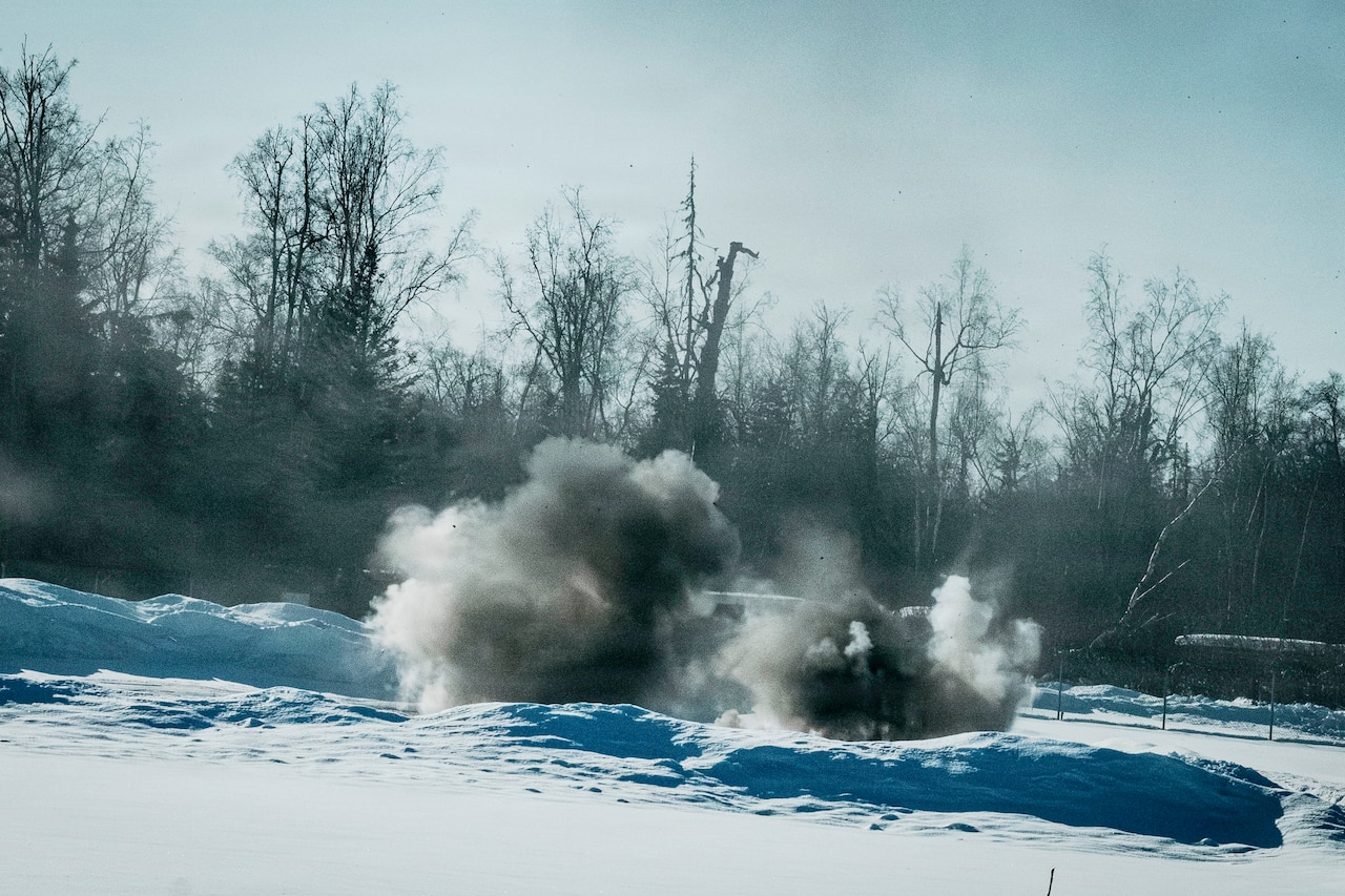 Two clouds of smoke rise from a snow-covered ground.