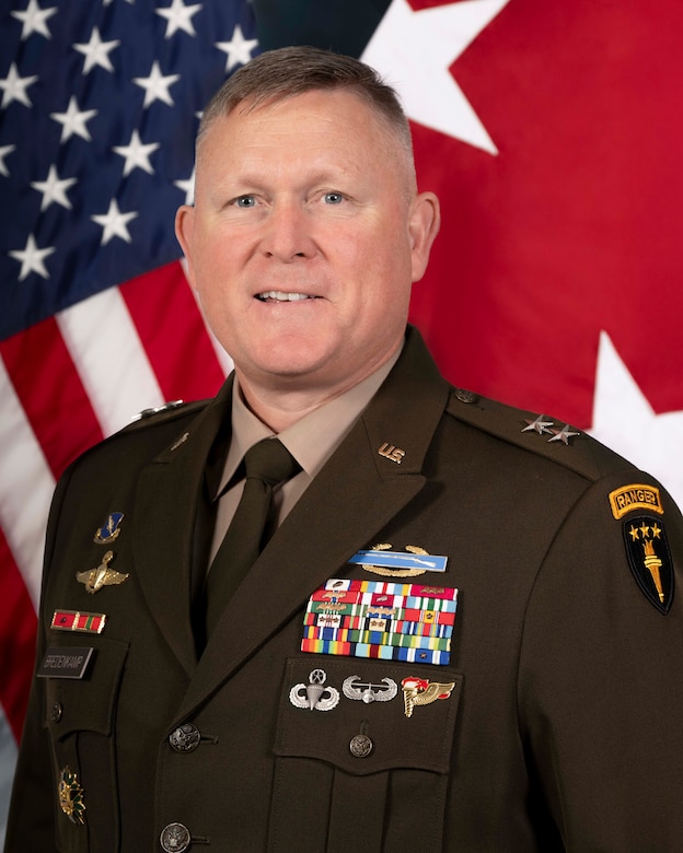Photo of a Major General in front of the American flag and two star flag in uniform.