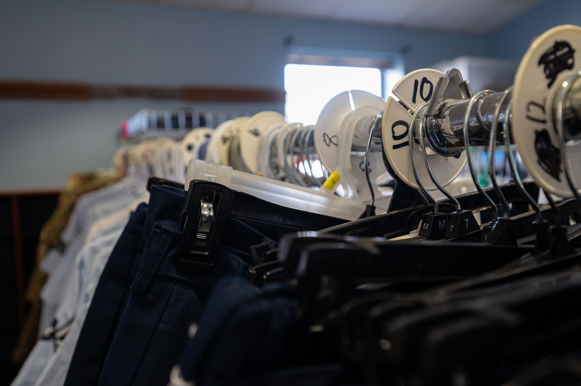 Service dress uniforms hang on a rack at the Airmen’s Attic on Dover Air Force Base, Delaware, March 2, 2026. Service dress uniforms can be donated to the Airmen’s Attic, helping Airmen who may not be able to purchase brand-new ones. (U.S. Air Force photo by Airman 1st Class Liberty Kuhn)
