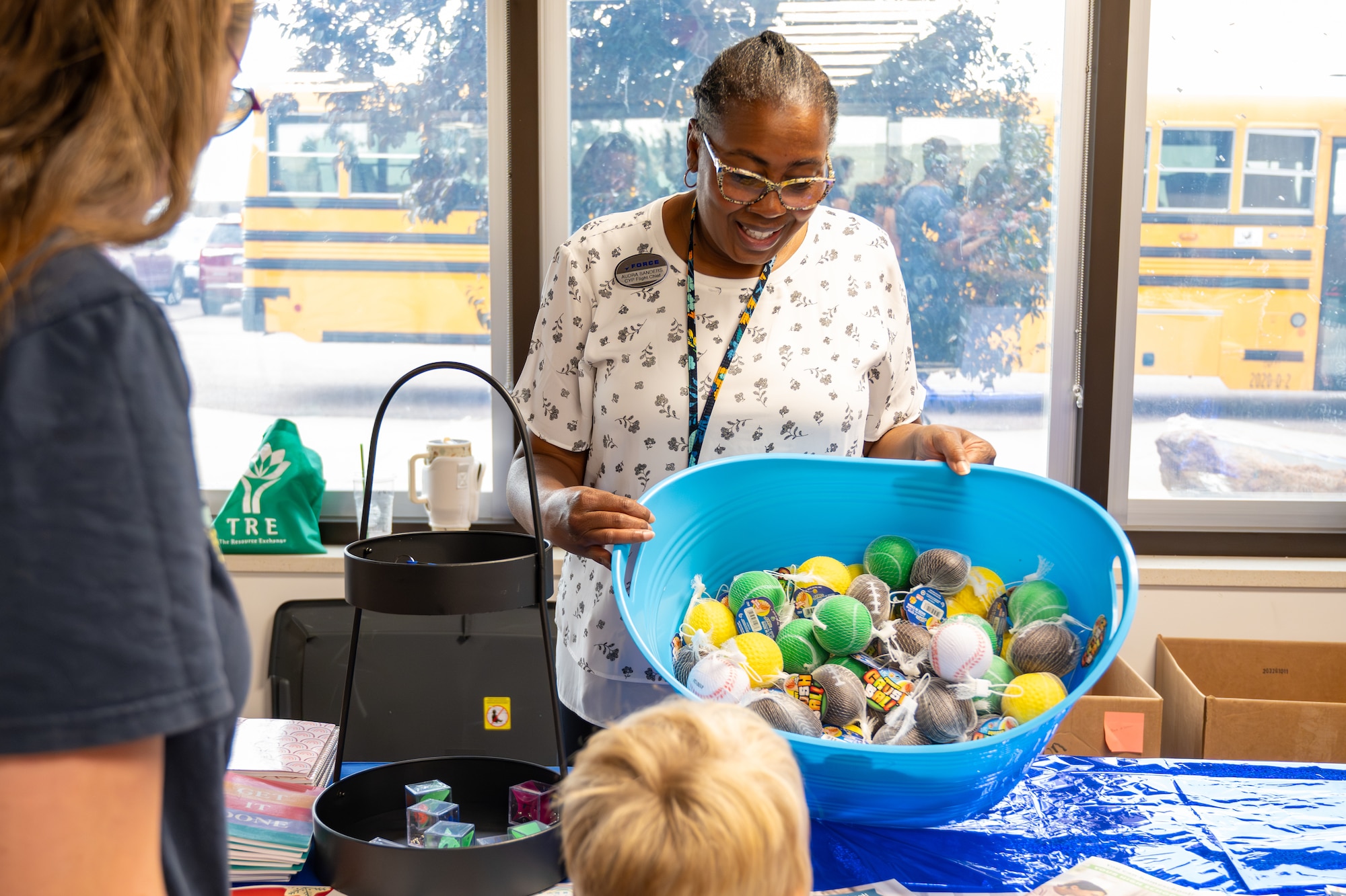 A supervisory child and youth specialist presents a bin of toys to a dependent during a Back-to-School Bash.