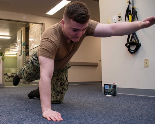 Hospital Corpsman Conor Tucker from the Naval Medical Center Portsmouth's physical therapy department demonstrates physical therapy moves while the Sword Thrive technology monitors his form and suggests corrections.