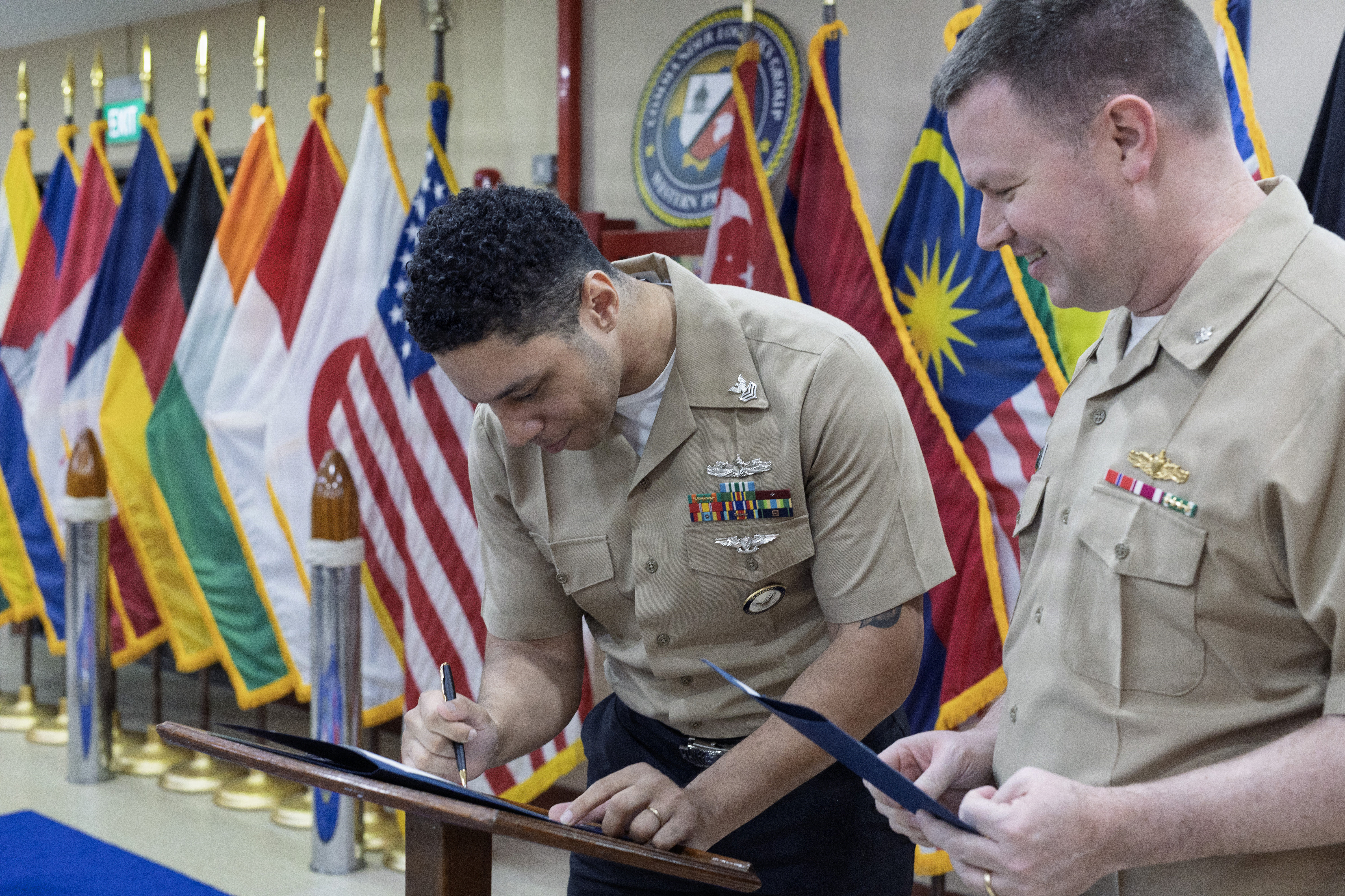 Yeoman 1st Class Robert J. Carter, administrative officer assistant, Military Sealift Command (MSC) Far East, signs re-enlistment documents prior to his re-enlistment ceremony at MSC Far East headquarters, Singapore Naval Installation, Singapore, Feb. 26, 2026.